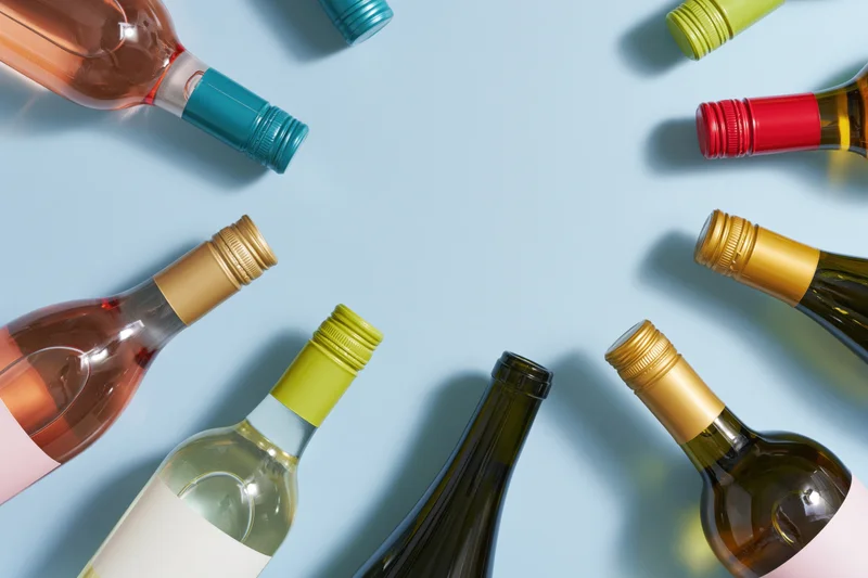 Wine bottles arranged neck-inward around frame edges on light blue background with central copyspace
