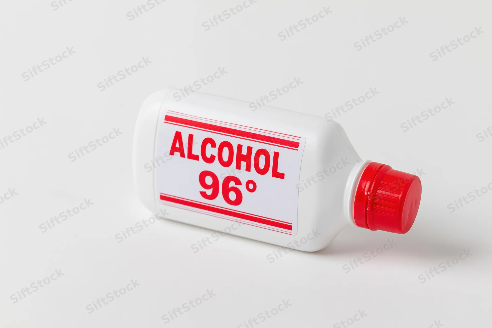 White plastic bottle of 96-degree rubbing alcohol lying on a plain white surface