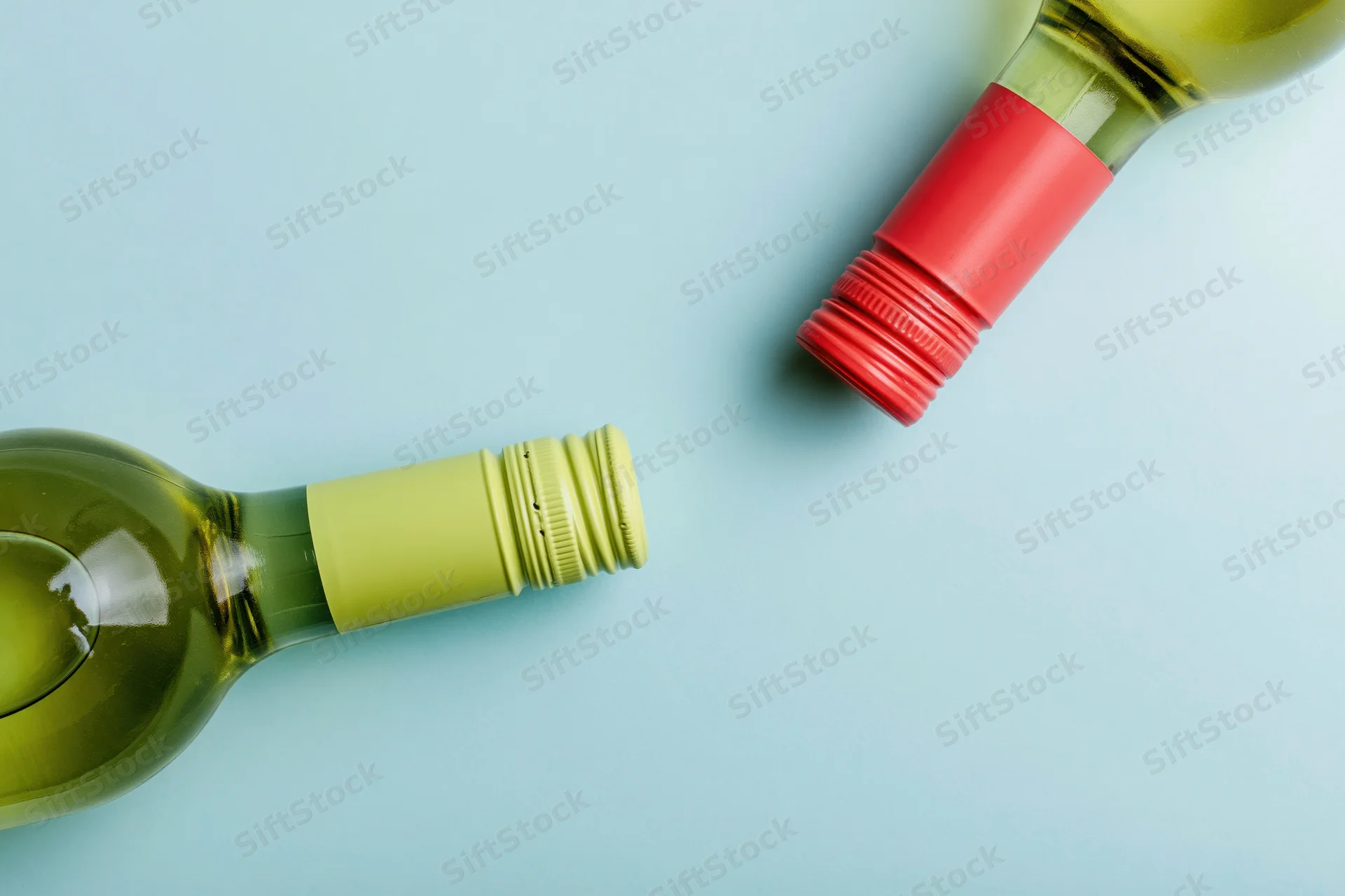 Two wine bottles lying flat on a light blue surface with copyspace