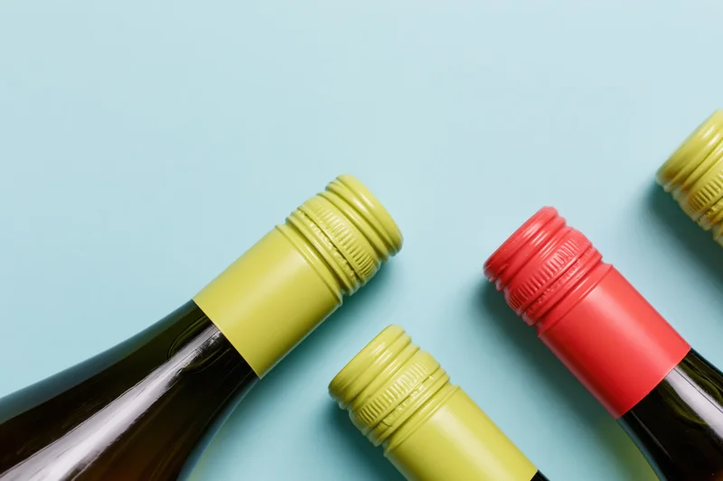 Wine bottles lying flat on a blue background with yellow and red caps, top view