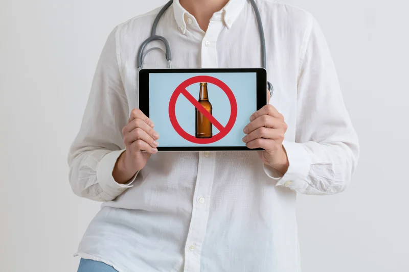 Doctor holding tablet with no alcohol symbol on screen