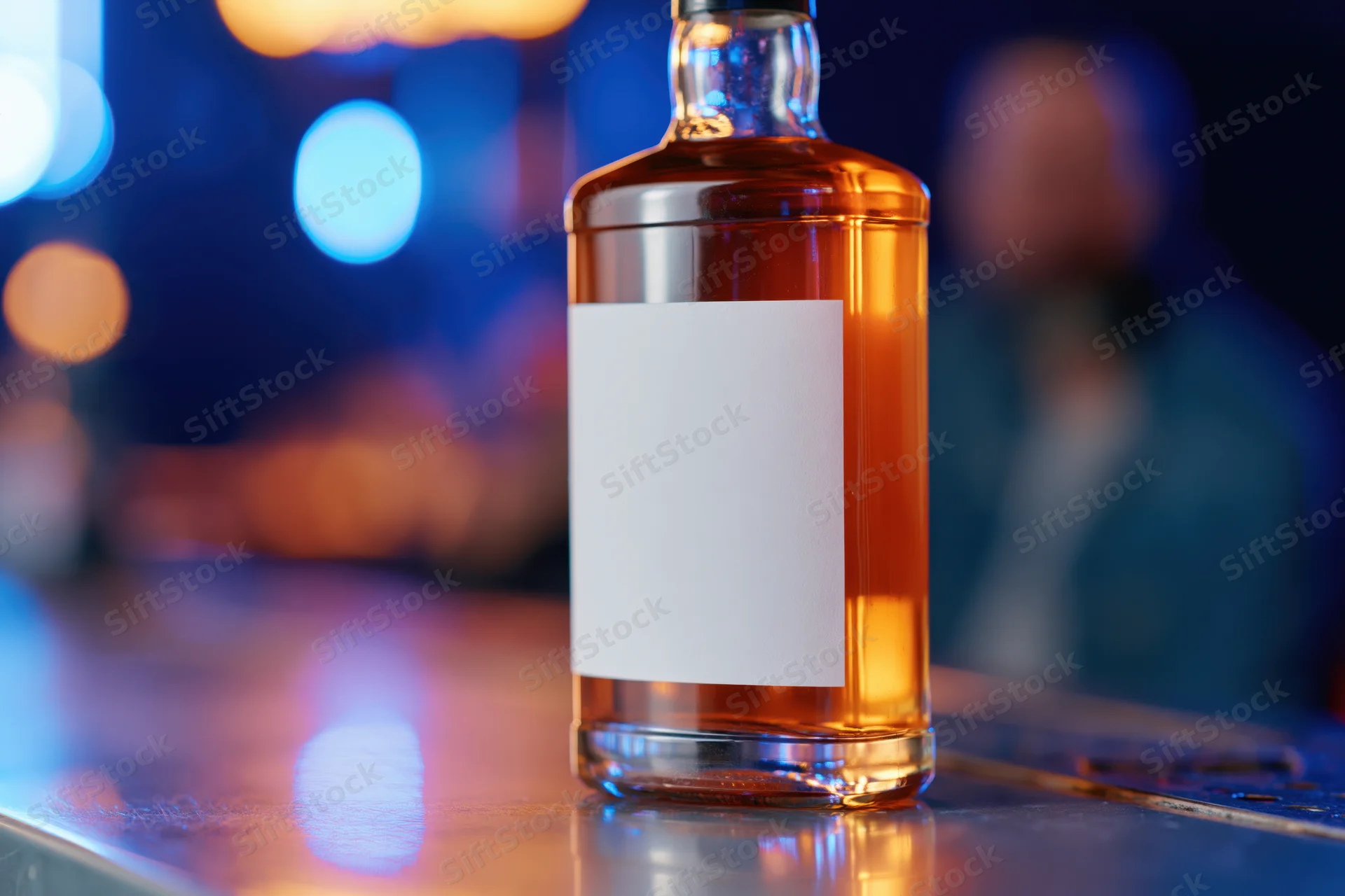 Whiskey bottle with blank label on bar counter at night