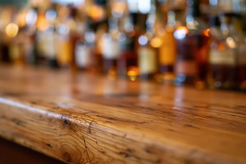 Wooden bar counter with blurred bottles in background