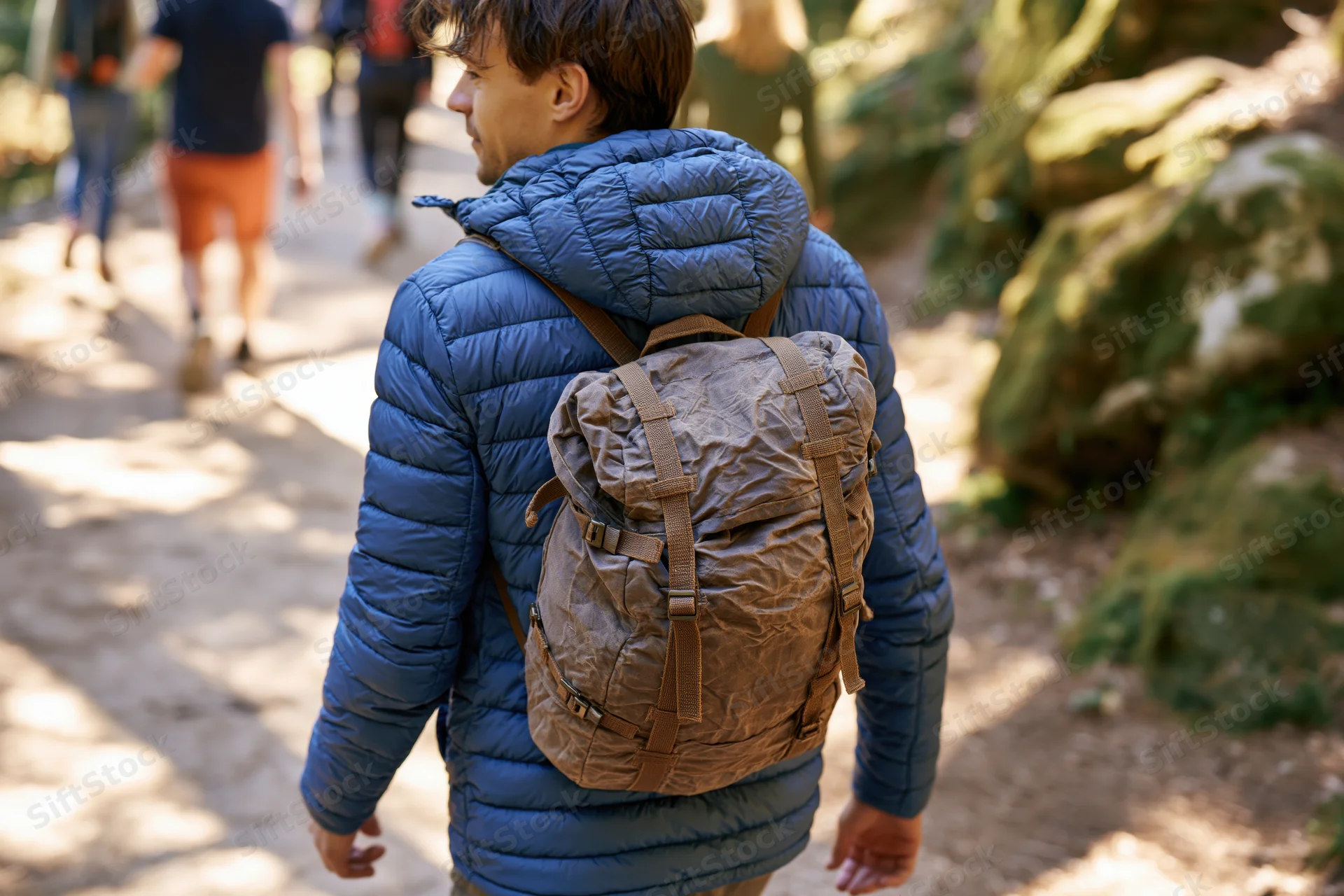 Man hiking on forest trail with backpack, surrounded by trees and sunlight