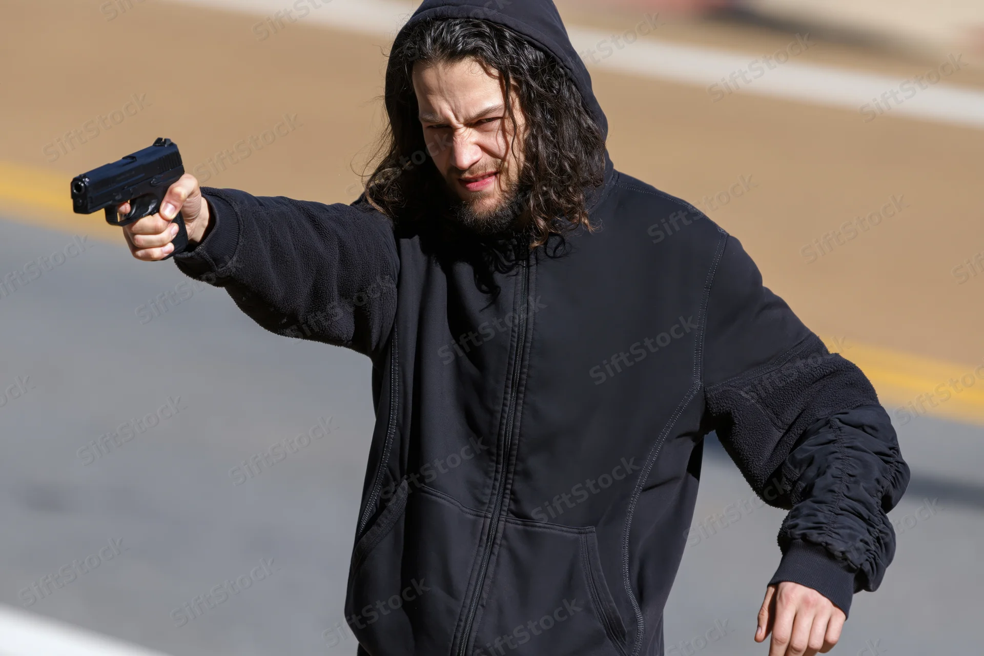 Man aiming handgun on street in daylight