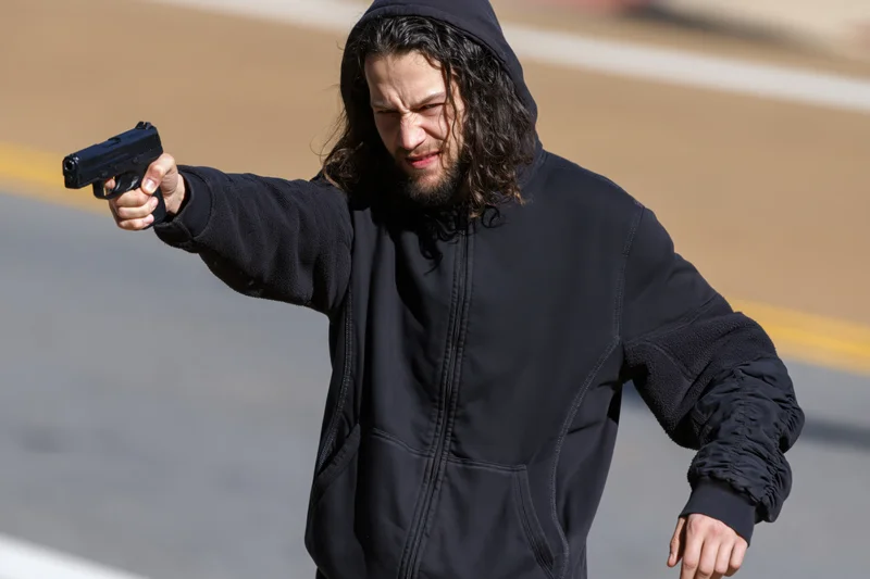 Man aiming handgun on street in daylight