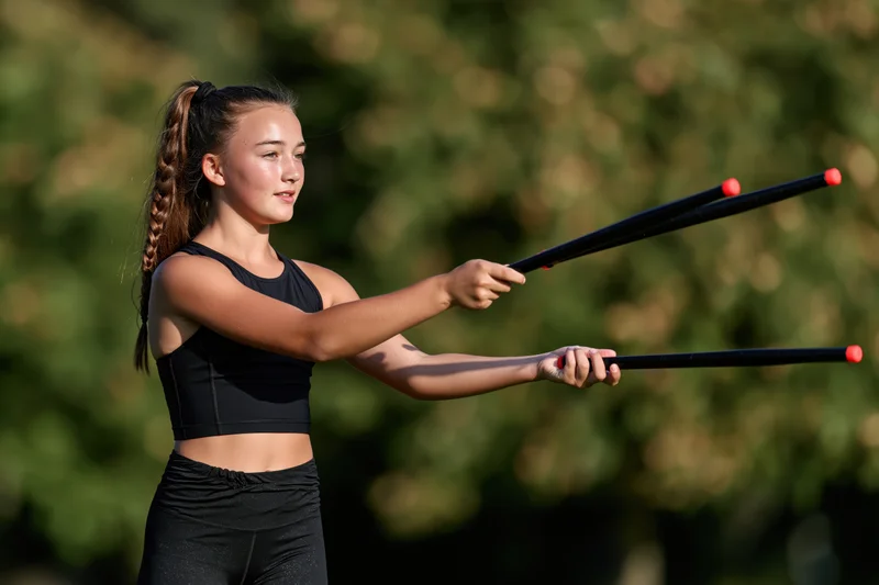 Young girl twirling batons outdoors in a park during daytime