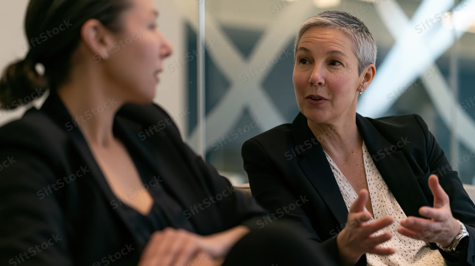 Two professional women in conversation in a modern office setting