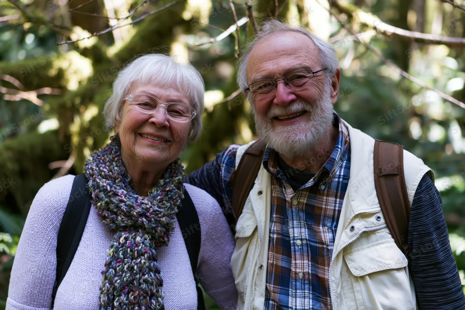 Elderly couple smiling together in a mossy forest while hiking