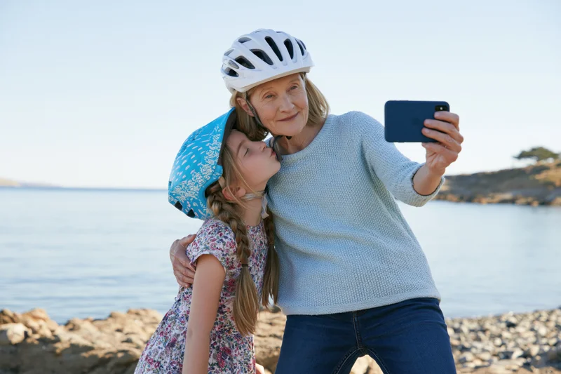 Grandmother and granddaughter taking a selfie together on a rocky beach by the ocean