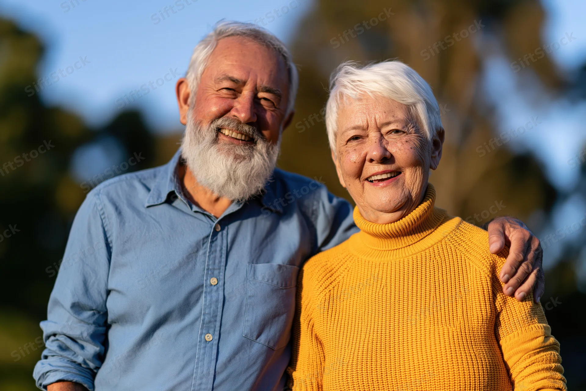 Elderly couple smiling together outdoors in late afternoon light