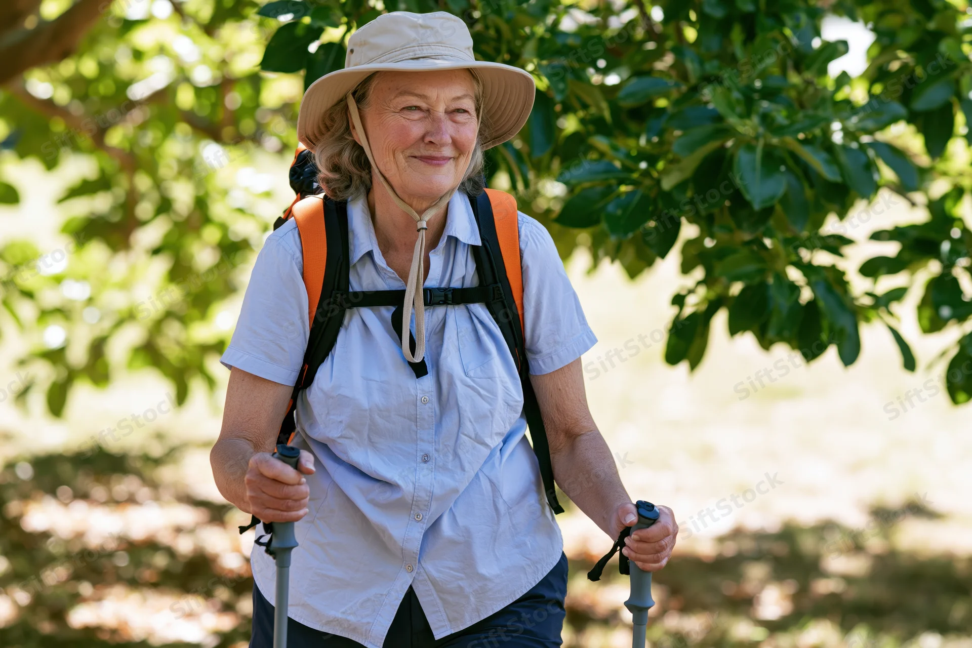 Senior woman hiking with backpack and trekking poles on a sunlit forest trail