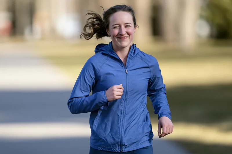 Woman running in a park smiling with windblown hair