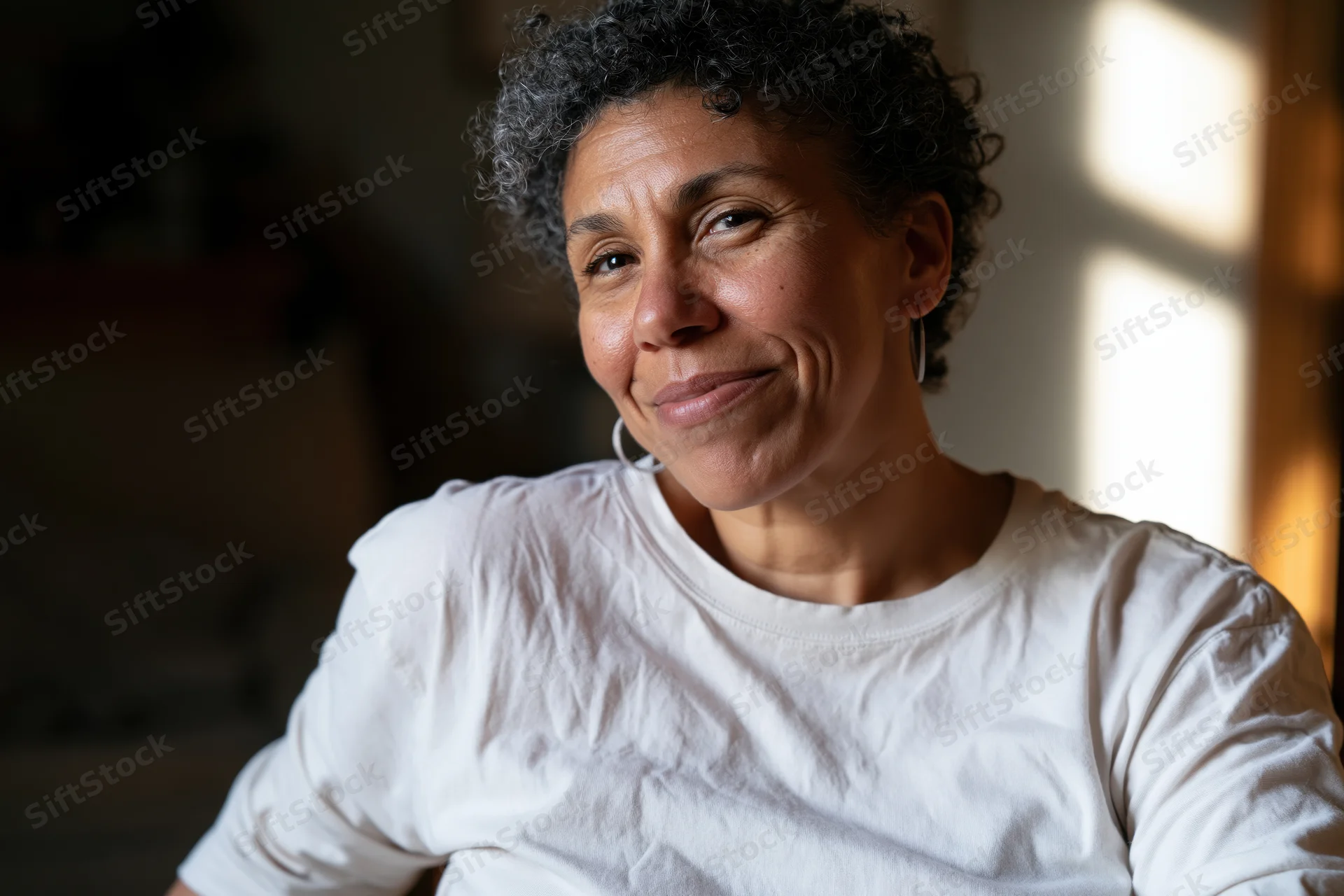 Middle-aged black woman smiling softly in natural light indoors