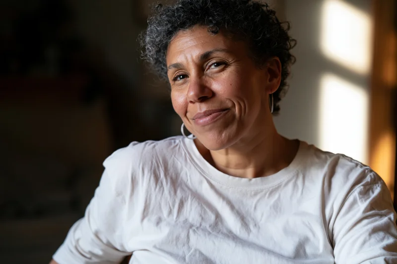 Middle-aged black woman smiling softly in natural light indoors