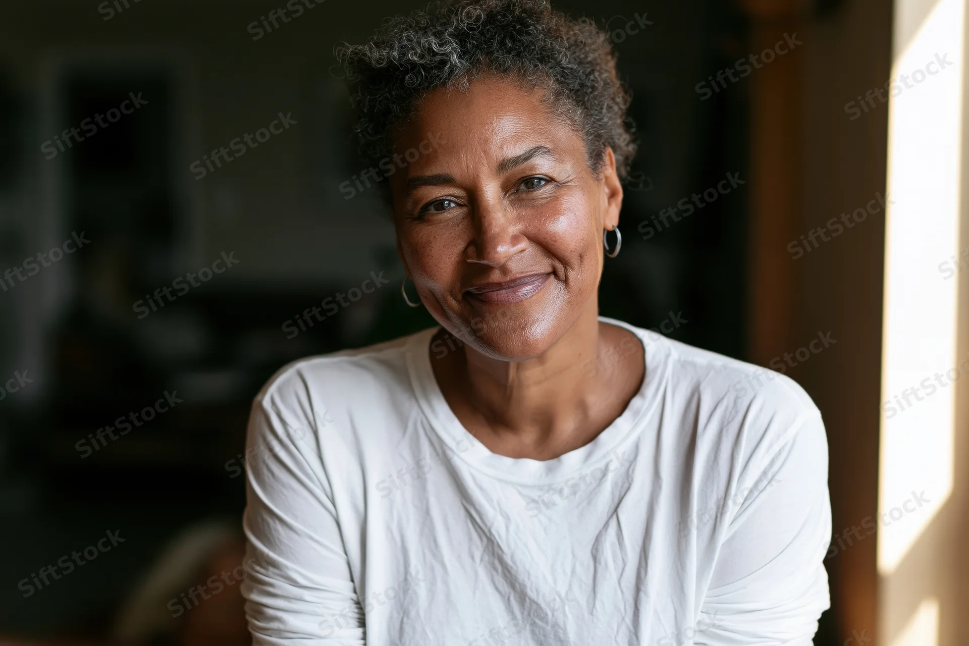 Middle-aged black woman smiling in a candid portrait indoors by a window