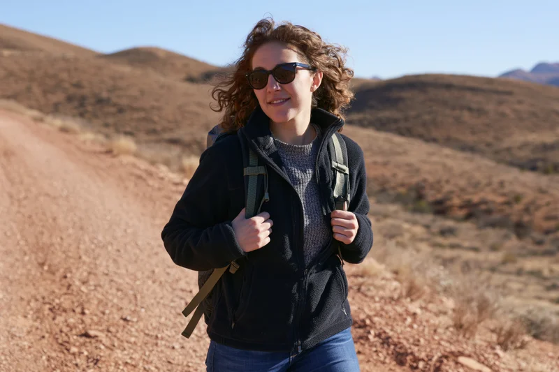 Woman hiking on a desert trail with backpack and sunglasses
