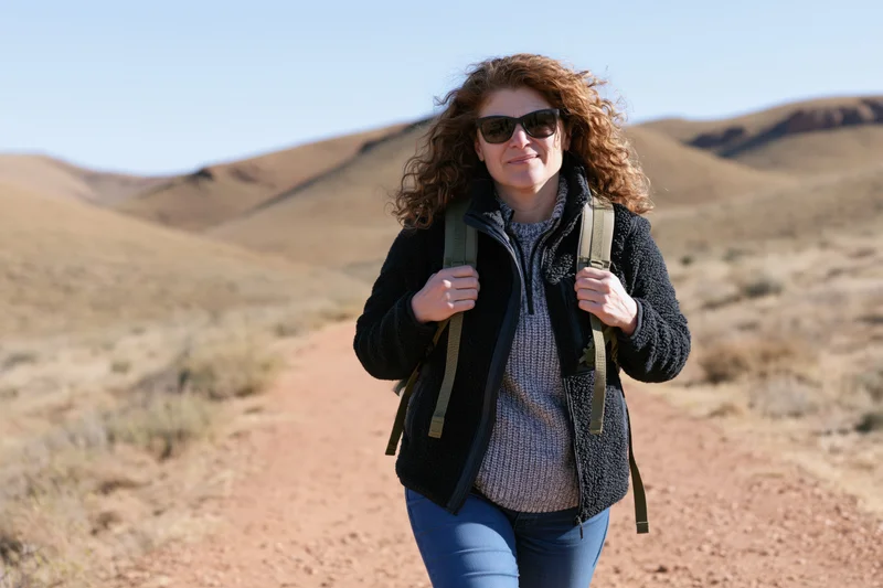 Woman hiking on a desert trail with backpack and sunglasses
