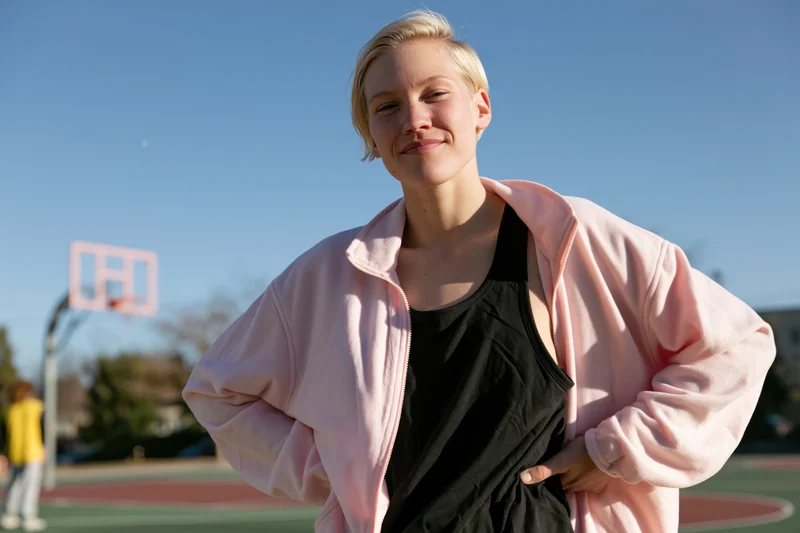 Woman with short blonde hair smiling casually on a basketball court outdoors