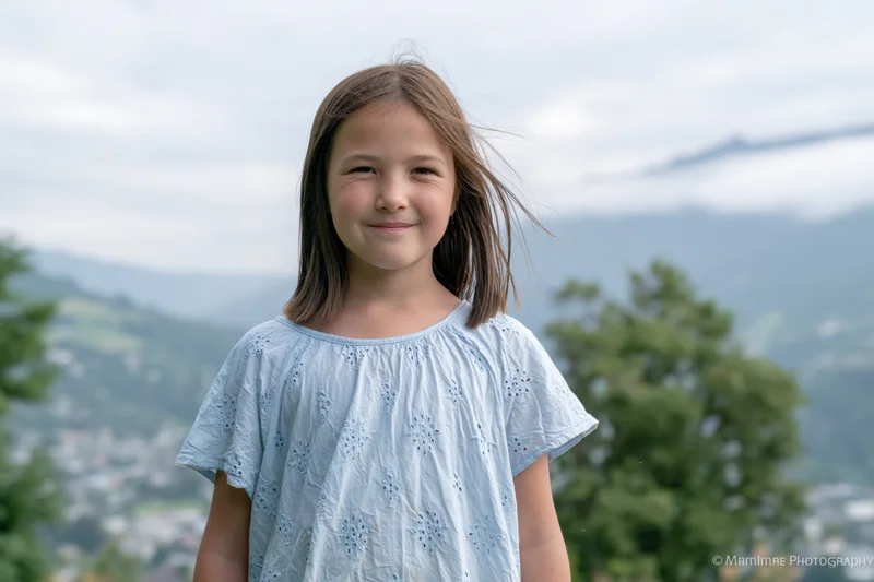 Young girl smiling outdoors with mountains and trees in the background