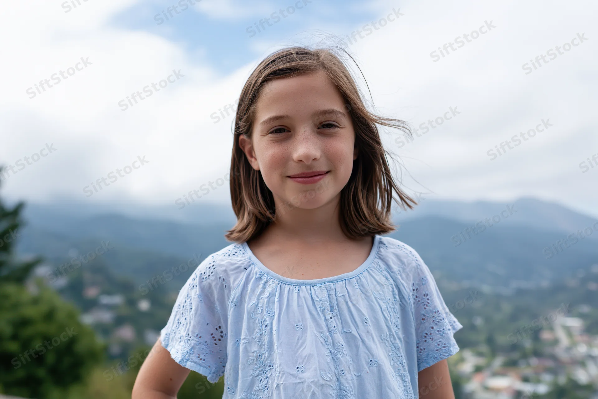 Young girl smiling outdoors with mountains and town in the background