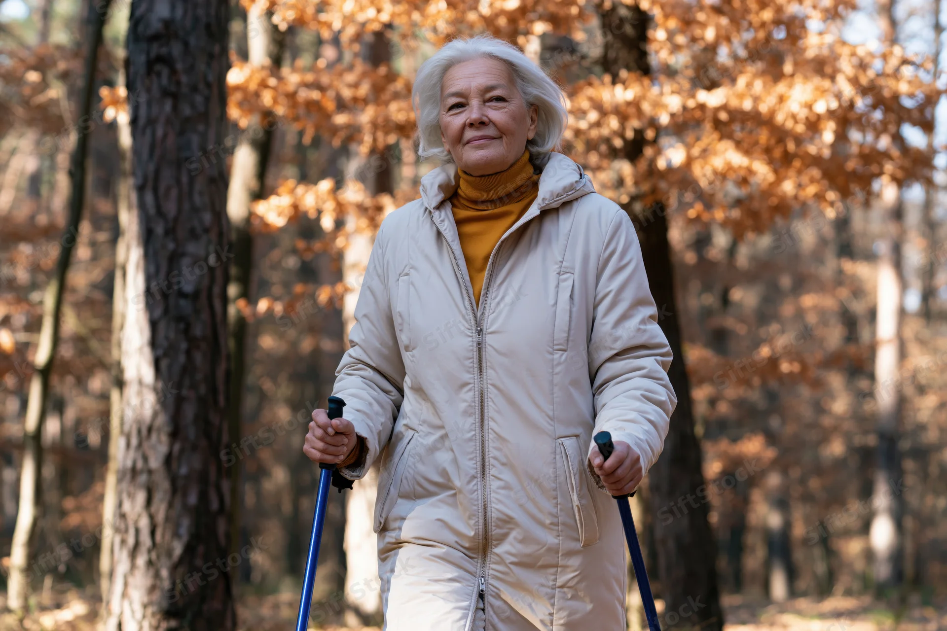 Senior woman walking with nordic poles in autumn forest