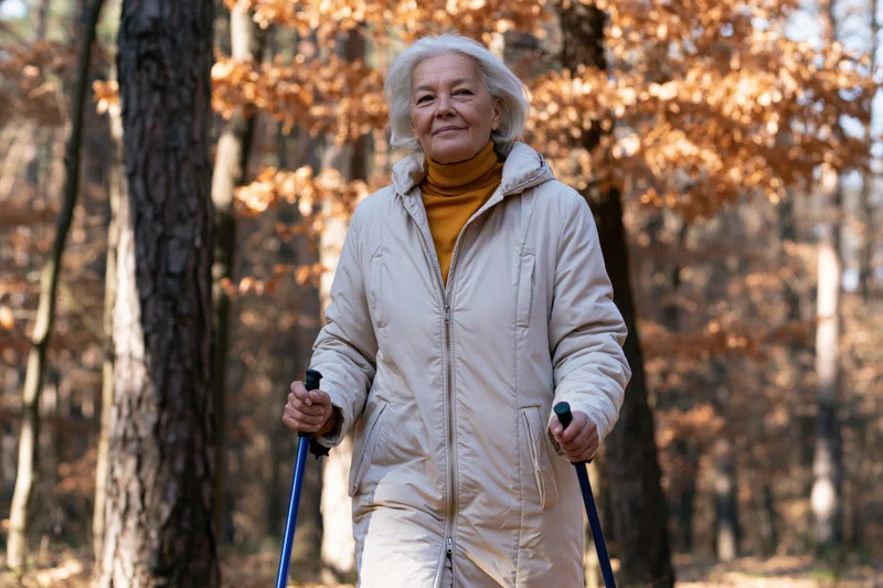 Senior woman walking with nordic poles in autumn forest