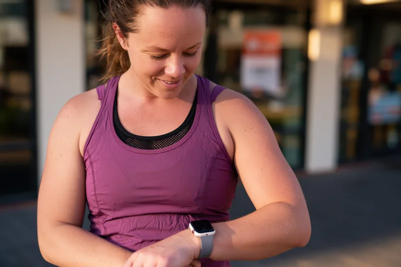 Woman checking smartwatch during outdoor workout in urban setting