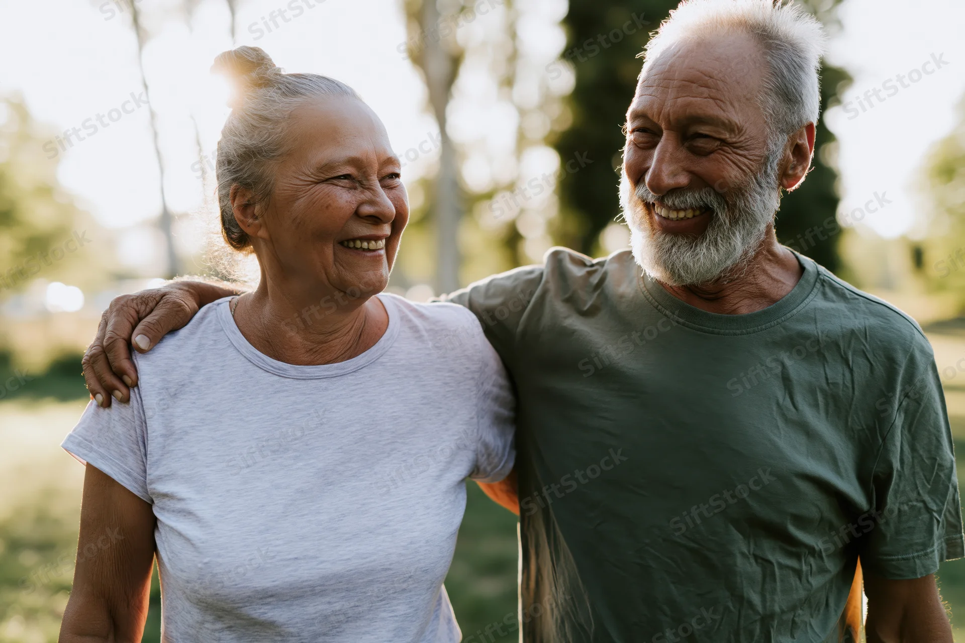 Elderly couple smiling and embracing outdoors in a park during golden hour