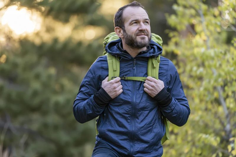 Man hiking with backpack in sunlit forest