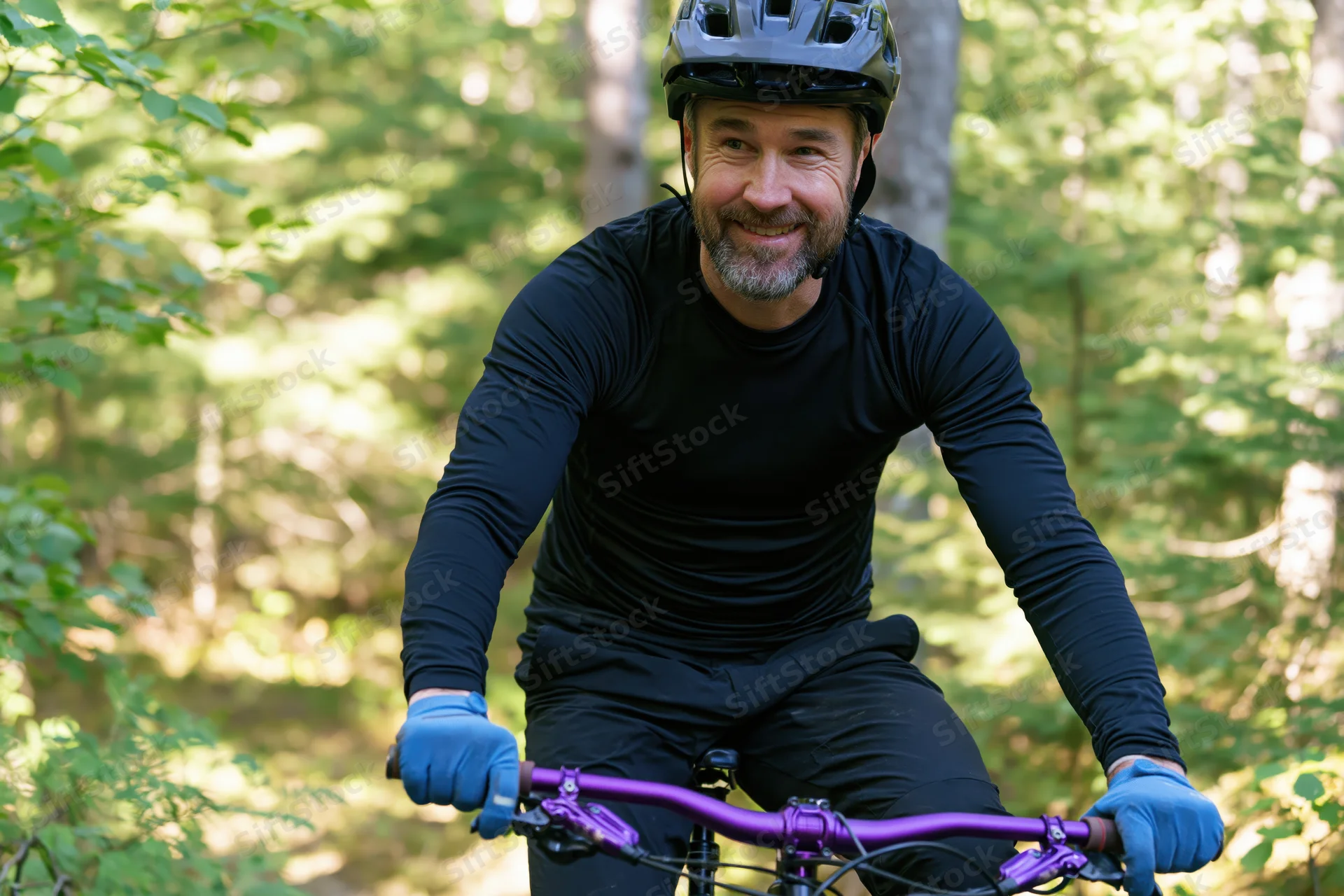 Man smiling while riding mountain bike on forest trail