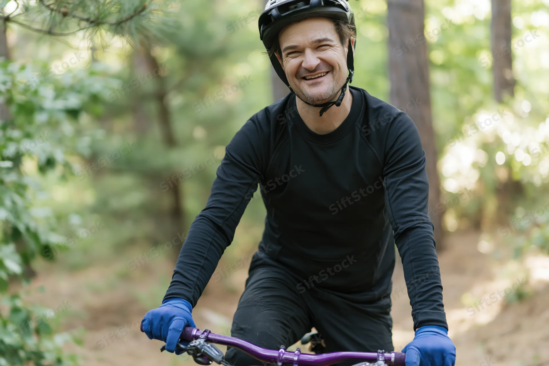 Man riding mountain bike on forest trail wearing helmet and gloves