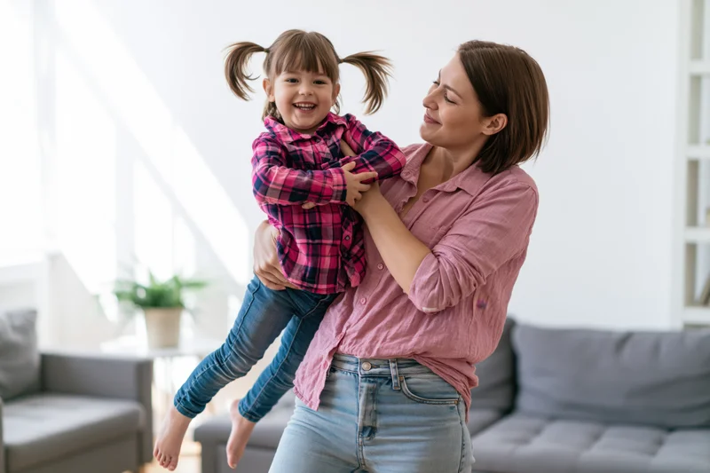 Woman holding child in playful hug in living room