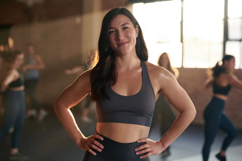 Woman smiling with hands on hips during group fitness class in studio