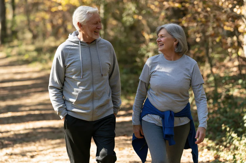 Elderly couple walking and smiling on a forest path in autumn