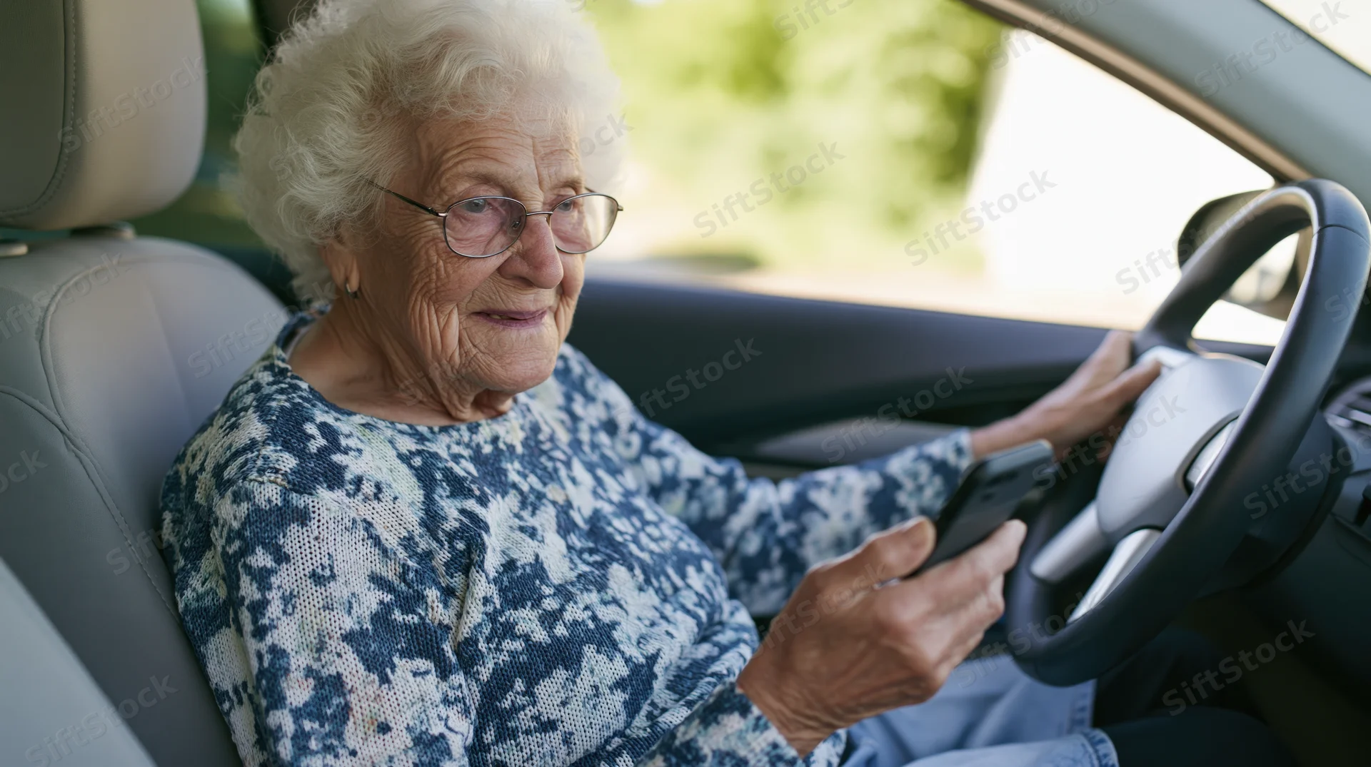 Elderly woman driving a car while holding a smartphone in her hand
