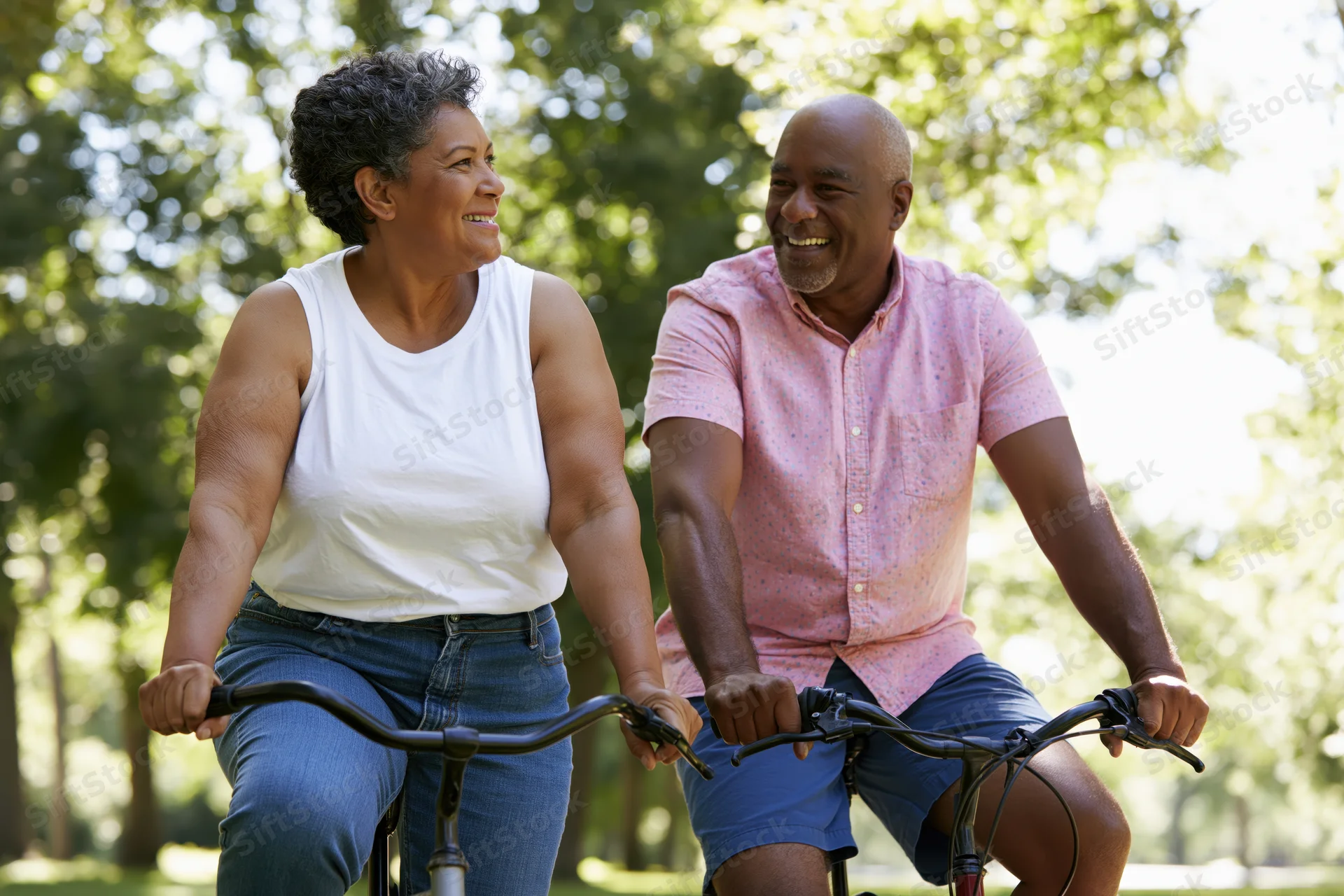 Senior africanamerican couple cycling together in a sunlit park smiling at each other