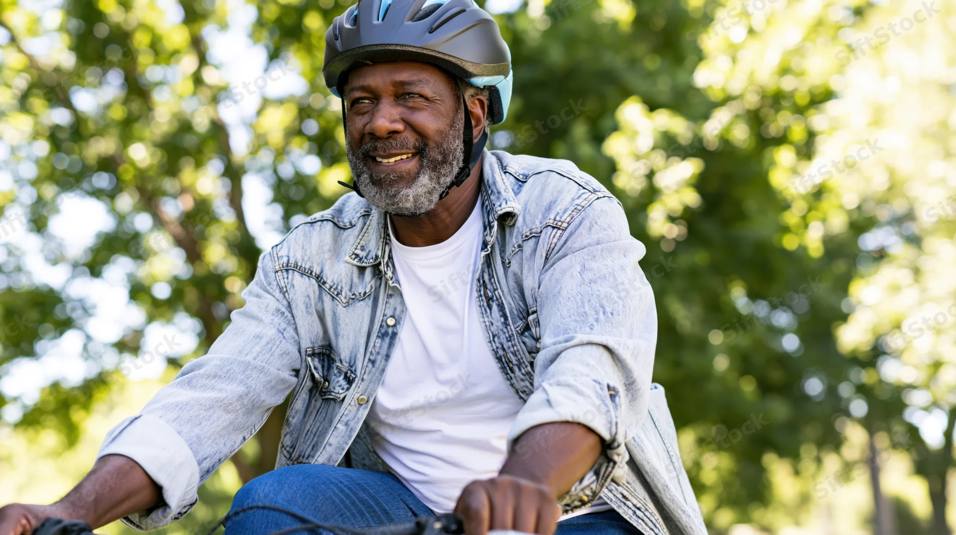 Senior black man smiling while cycling outdoors in a park