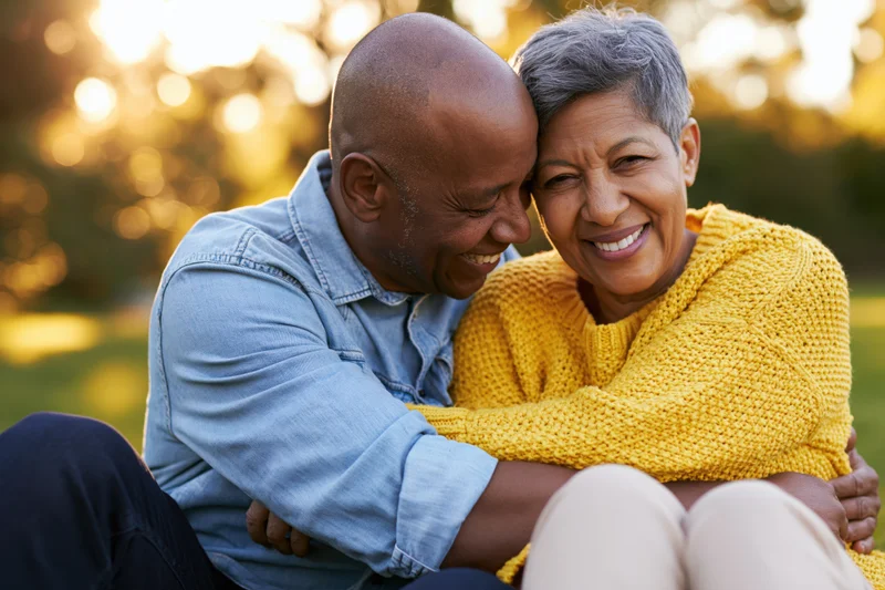 Senior african couple embracing and smiling in a park at sunset
