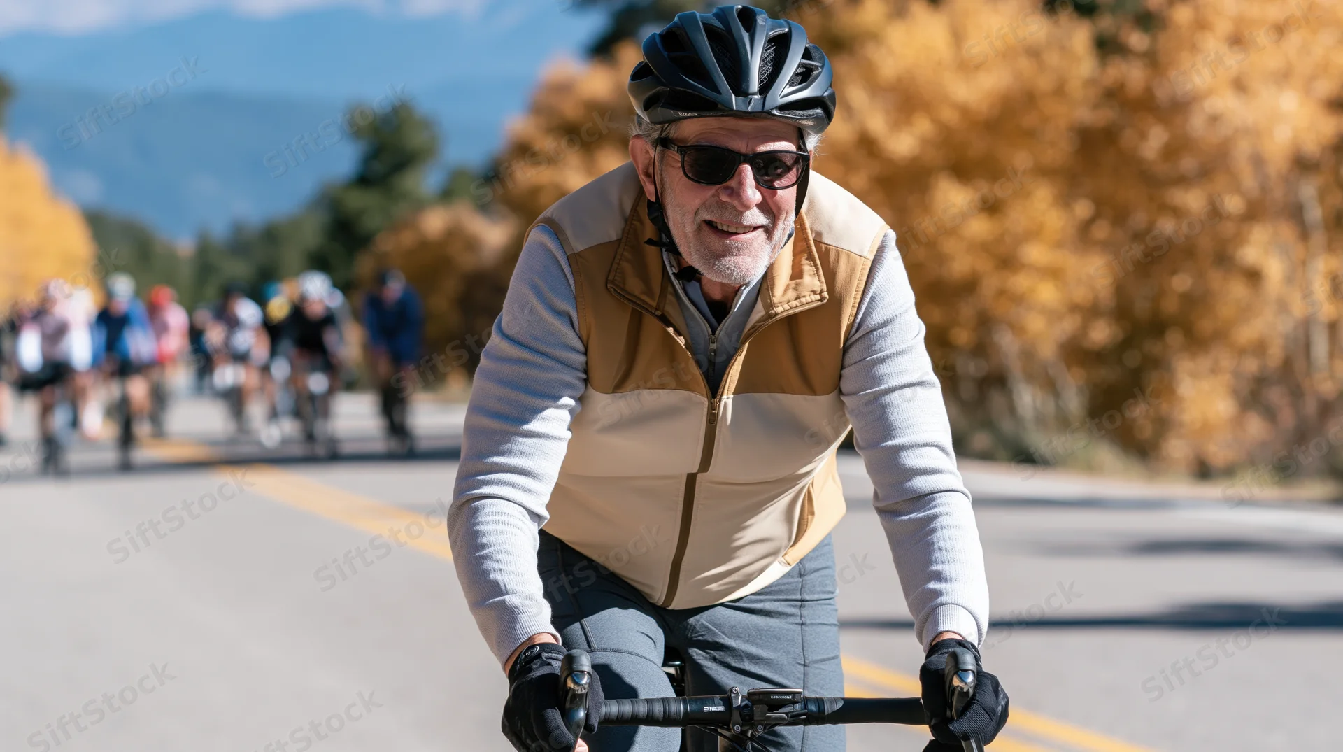 Senior man cycling on a paved road with autumn trees and mountains in the background