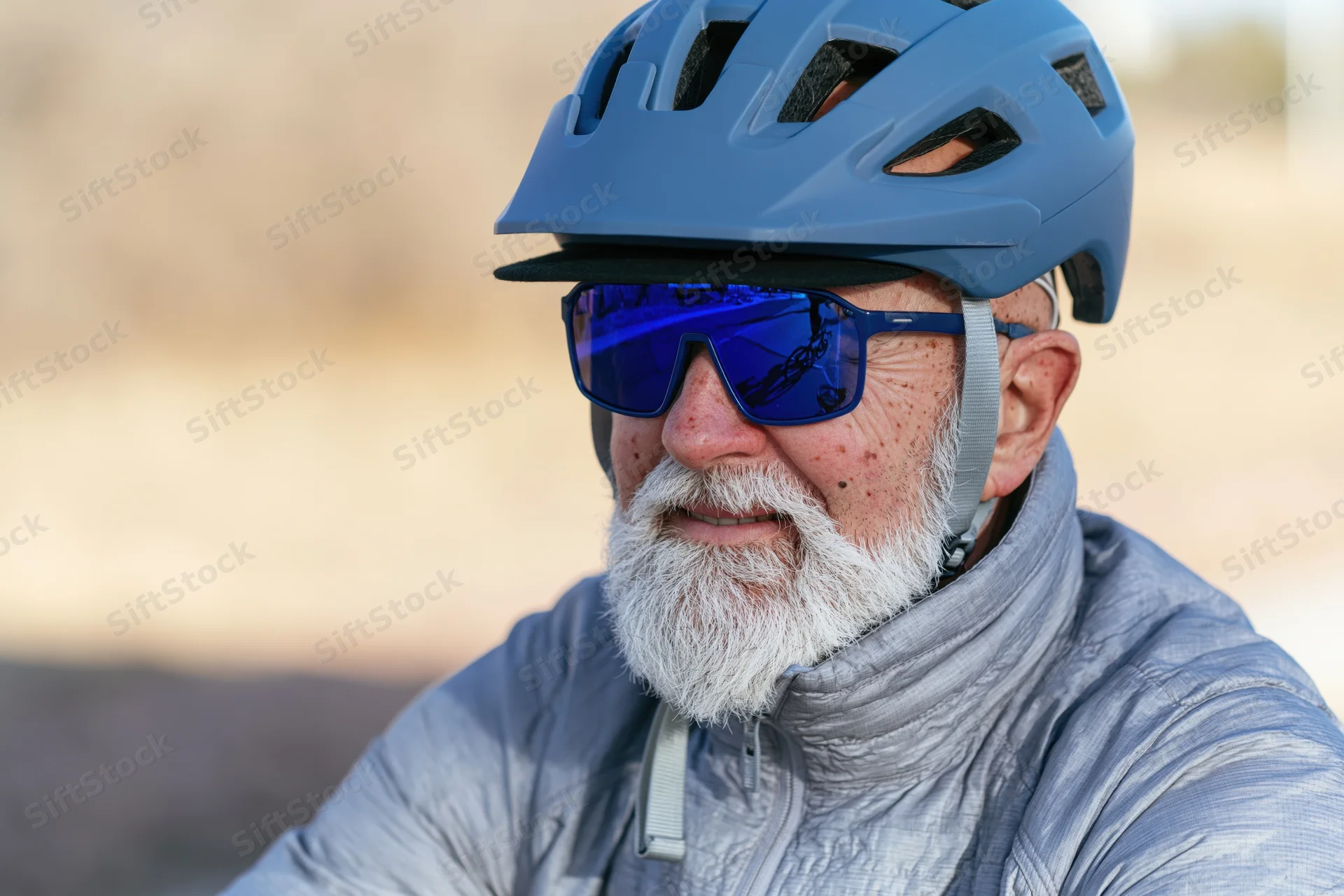 Senior man with white beard wearing blue helmet and sunglasses during outdoor cycling activity