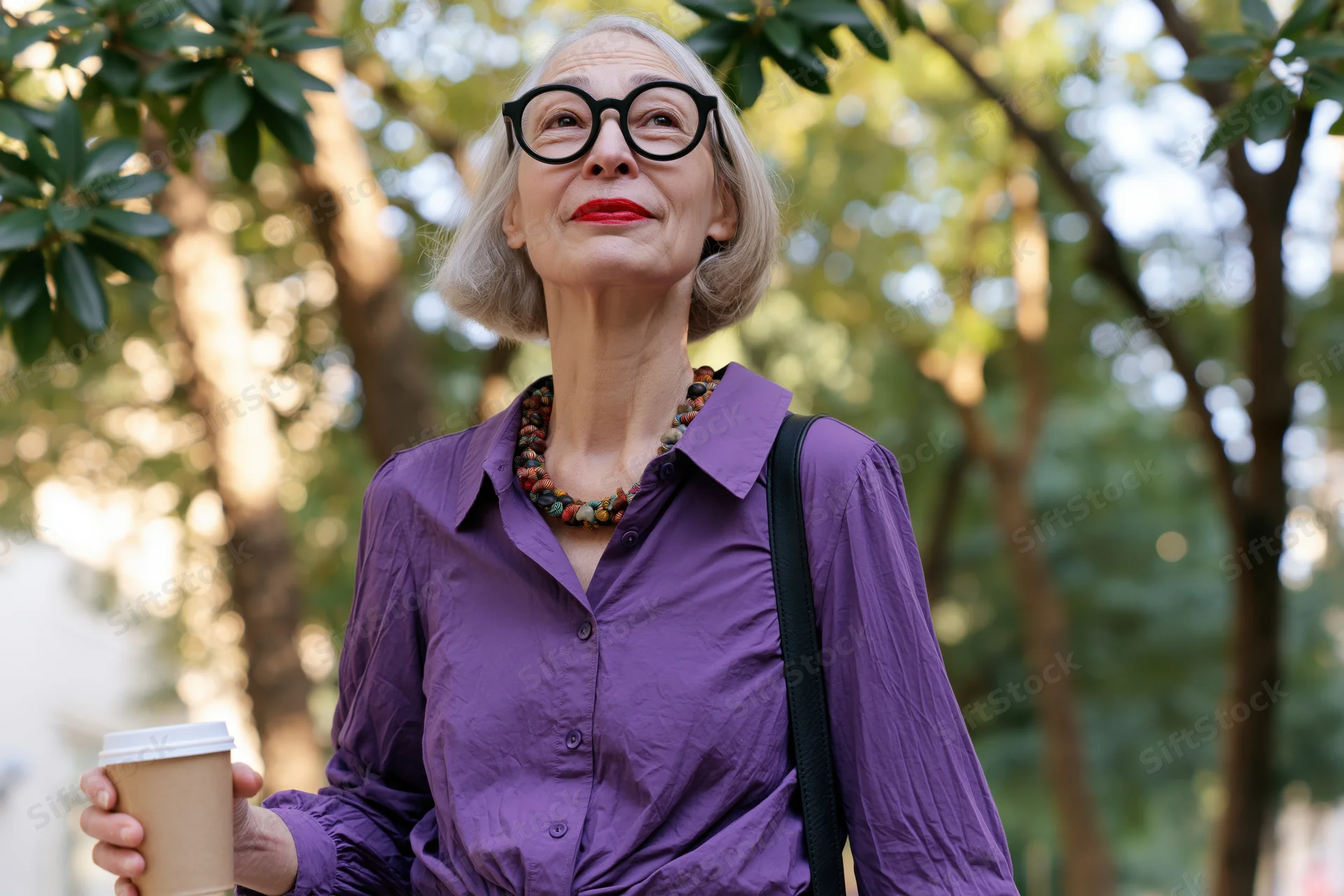 Senior woman holding coffee cup outdoors looking up through trees
