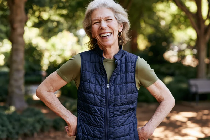 Senior woman smiling with hands on hips in a sunlit park