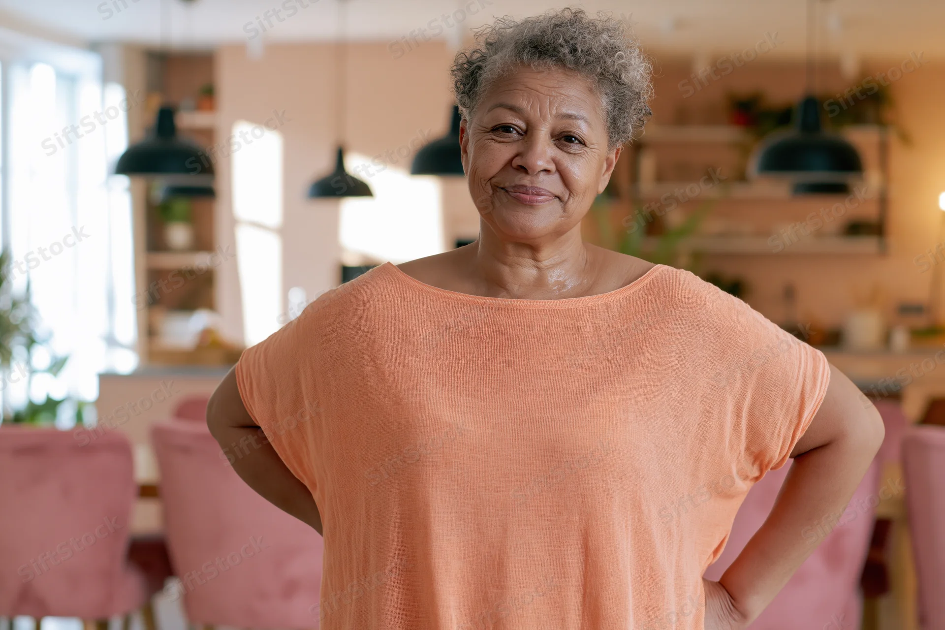 Senior woman smiling with hands on hips in a warm kitchen interior