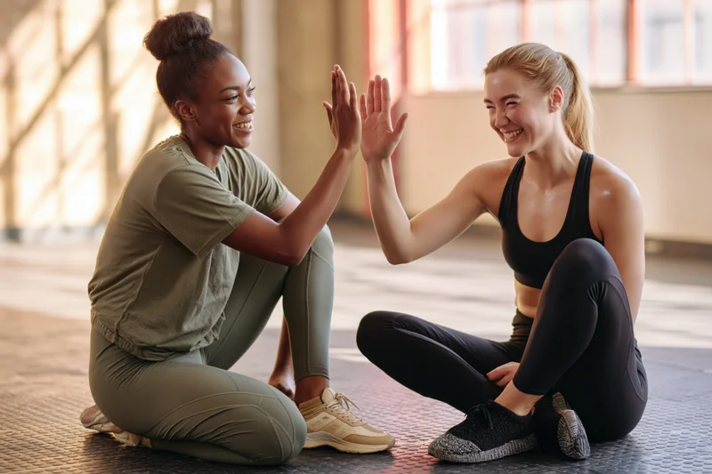 Two women in sportswear giving each other a high five on a gym mat