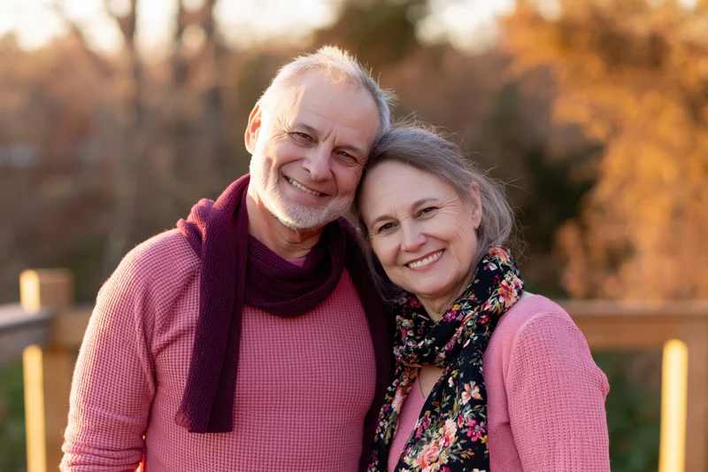 Older couple smiling and embracing outdoors in autumn light