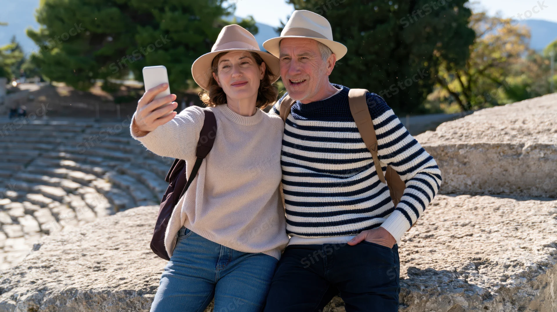 Older couple taking a selfie together outdoors at ancient amphitheater ruins