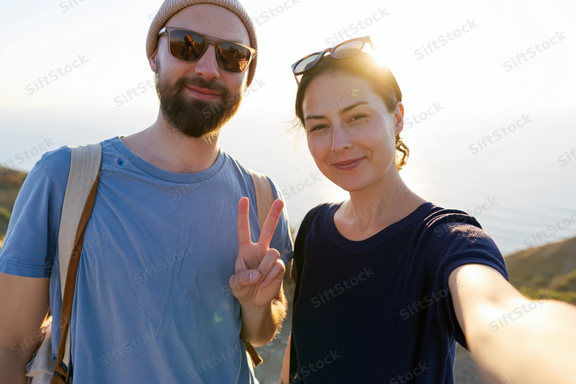 Couple taking a selfie outdoors with ocean and mountains in the background