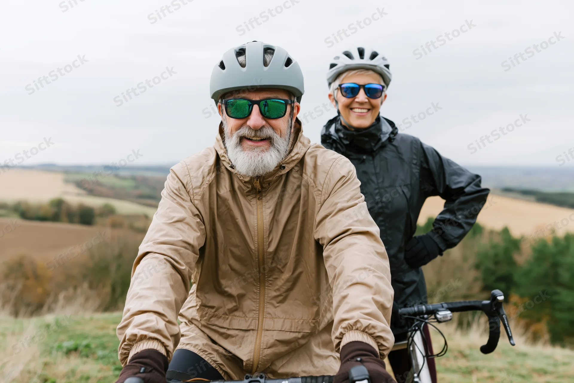 Senior man and woman cyclists smiling on a rural trail with bicycles, outdoors in autumn countryside