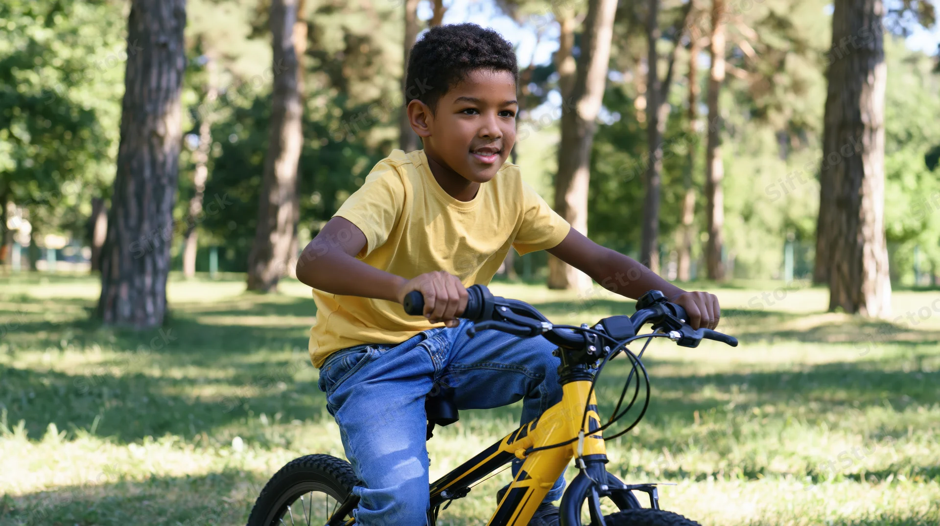 Boy riding bicycle in park smiling at camera